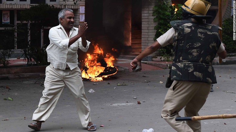 A follower of Indian religious leader Gurmeet Ram Rahim Singh pleads for his safety after being hit with a stick during clashes between the controversial guru&#39;s followers and security forces in Panchkula on August 25, 2017.