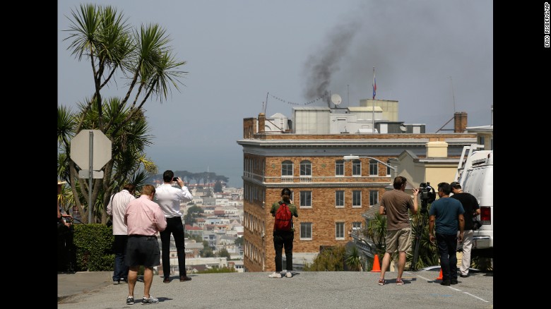 People stop to watch black smoke coming from the roof of the Russian consulate Friday in San Francisco. 