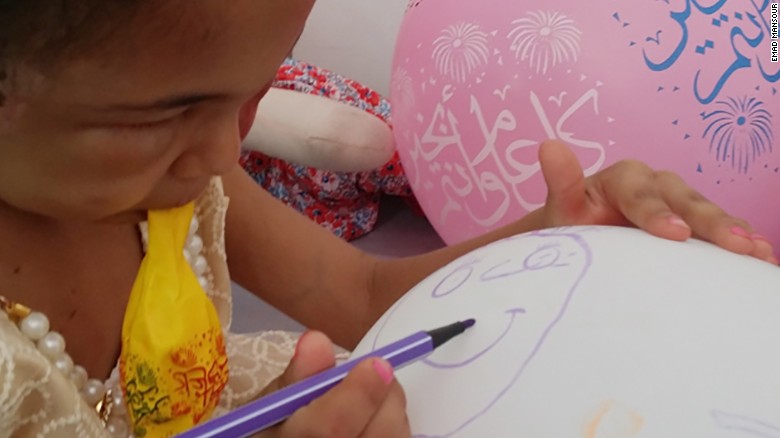 Buthaina draws on a balloon brought to her by one of her visitors. 