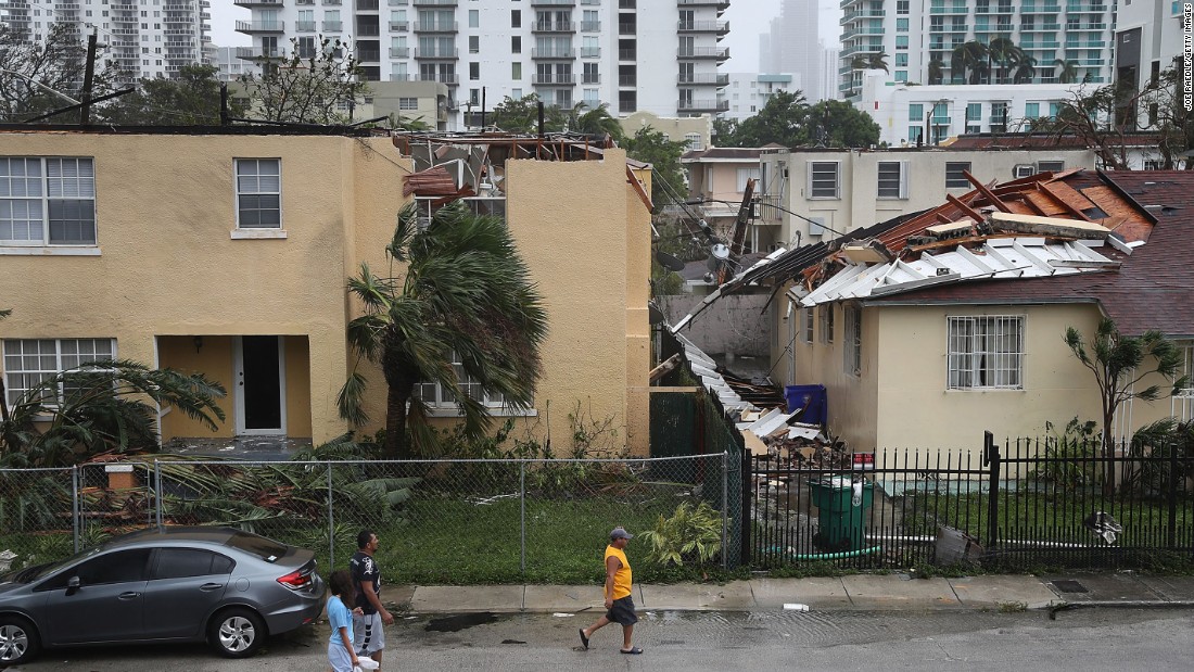 People walk past a building where the roof was blown off by Hurricane Irma in Miami.