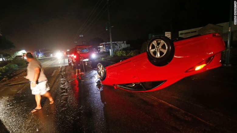 People tend to a car that flipped over on Cape Coral Parkway during Hurricane Irma, in Cape Coral, Florida, on Sunday, September 10. Irma made its second landfall in the state Sunday afternoon on nearby Marco Island as a dangerous Category 3 storm.