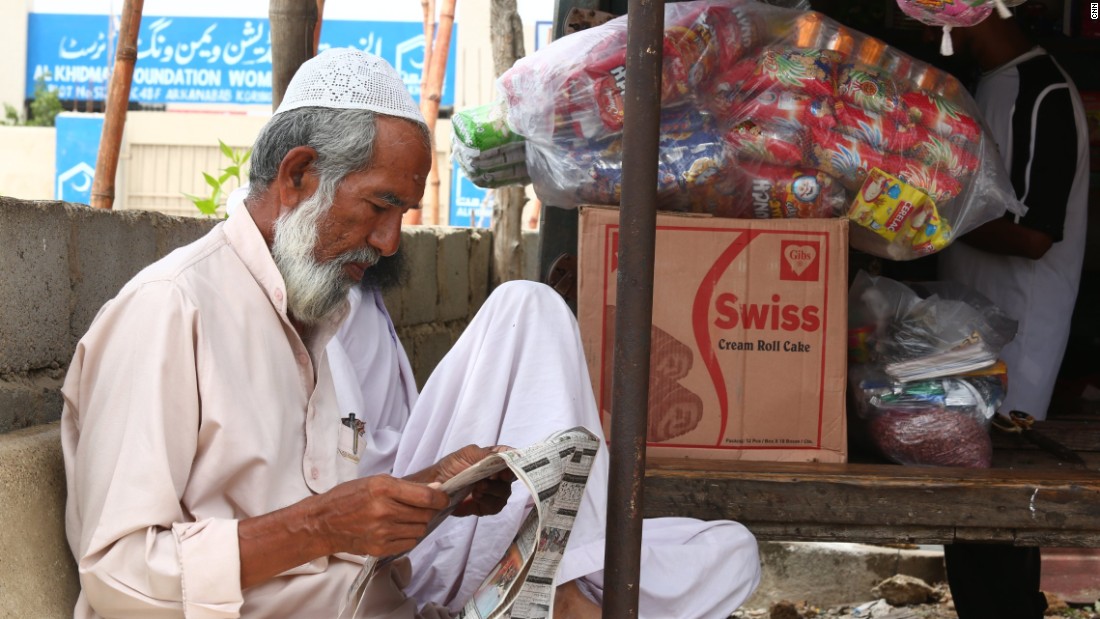 A Rohingya man reads a newspaper in the Arkanabad slum.