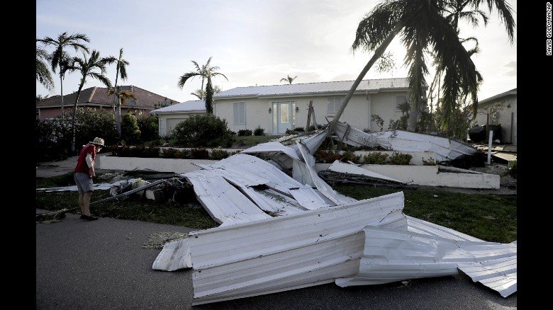 A roof is strewn across a home's lawn as Rick Freedman checks his neighbor's damage.