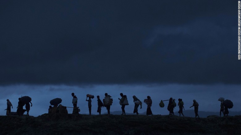Rohingya refugees walk across paddy fields at dusk after crossing the border from Myanmar.