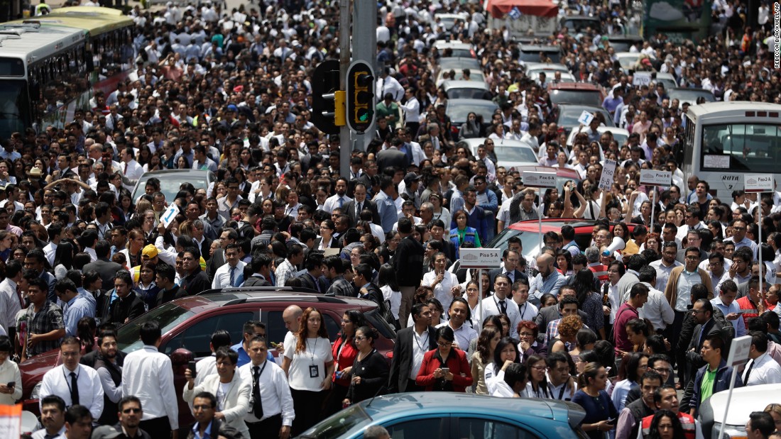 People gather on a Mexico City street after office buildings were evacuated because of the quake.