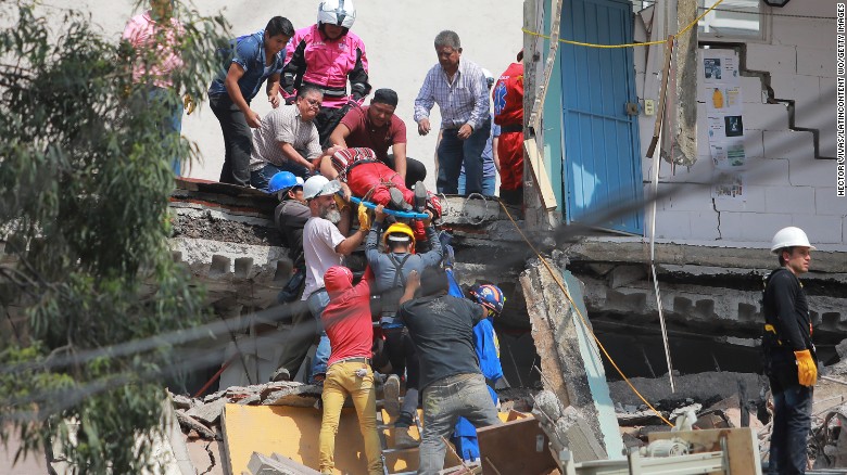 Rescuers and residents carry a woman to safety.