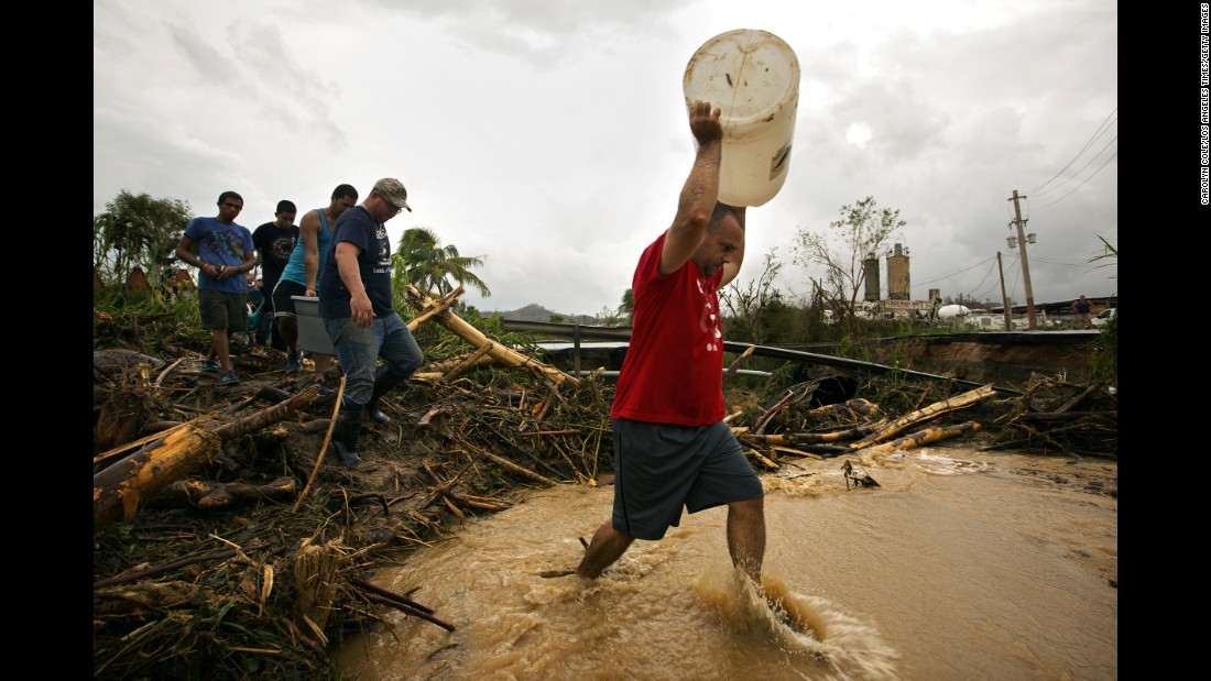 Residents in Utuado, Puerto Rico collect rain water from mountain springs and carry it through streams across broken roads.