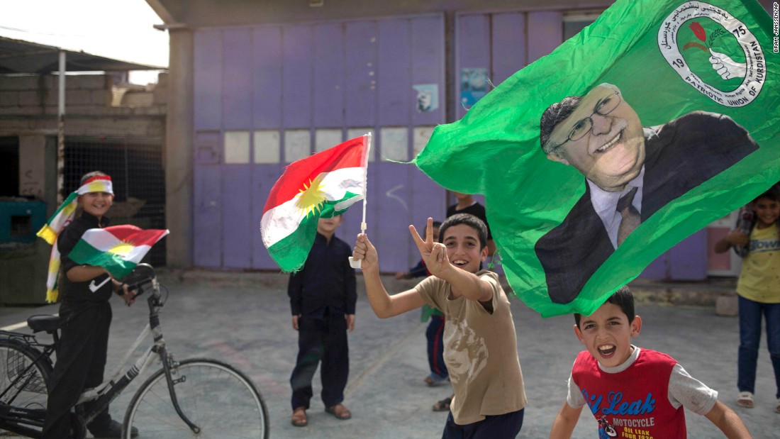 Children holding Kurdish flags run through the streets of Kirkuk on Monday.