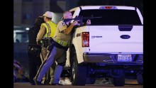 A police officer takes position behind a truck.