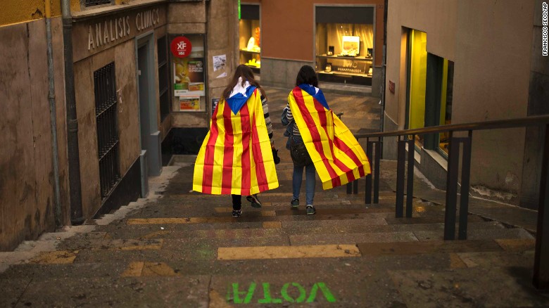 Women walk in the old quarter of Girona, Spain, draped in Catalonia&#39;s independence flag.