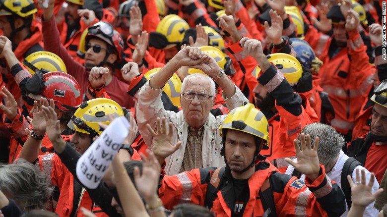 Protesters joined by firefighters raise their hands during the protest in Barcelona called by Catalan unions.