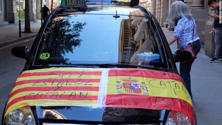 A car is adorned with Spanish and Catalan flags reading &quot;I am Spanish and Catalan&quot; and &quot;I am Catalan and Spanish.&quot;