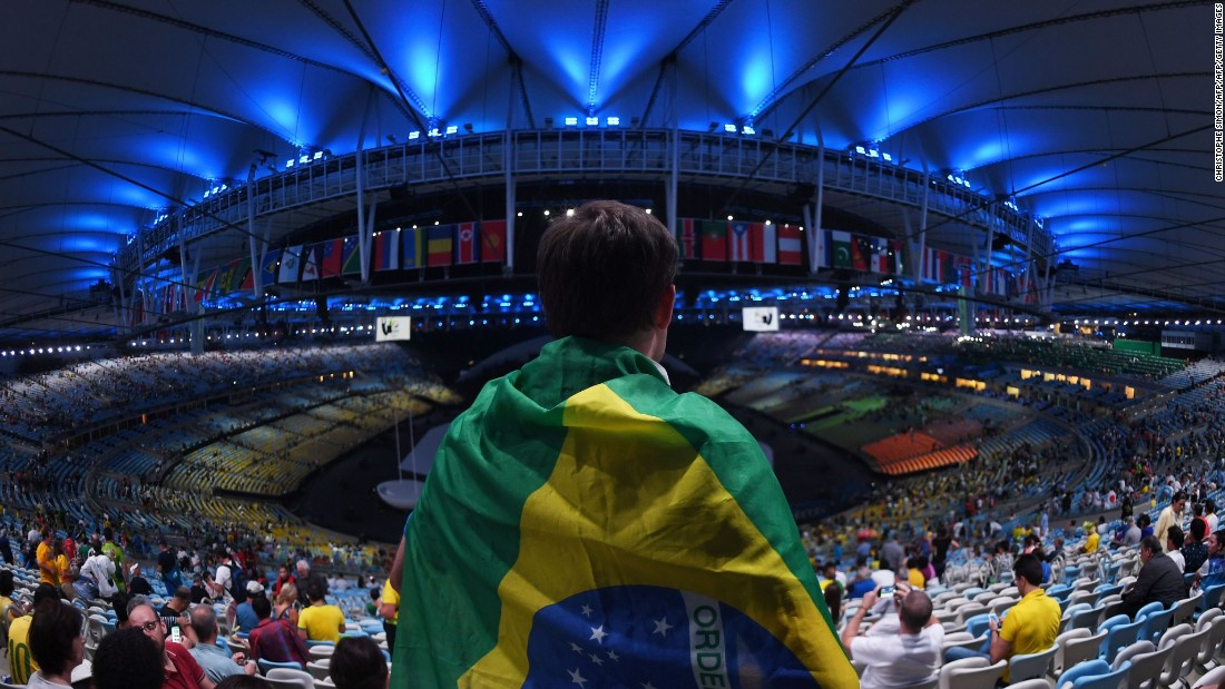 A spectator wrapped in a Brazilian flag looks on ahead the opening ceremony of the Rio 2016 Olympic Games at the Maracana stadium in Rio de Janeiro on August 5, 2016. / AFP / CHRISTOPHE SIMON        (Photo credit should read CHRISTOPHE SIMON/AFP/Getty Images)