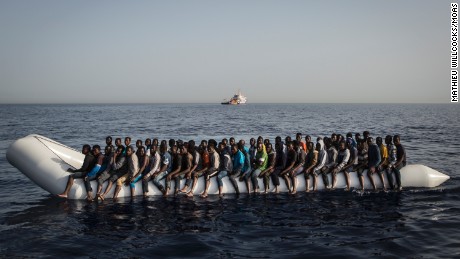 A rubber boat containing 125 migrants is seen at dawn off of the libyan coast, with MOAS&#39; topaz responder in the background.© Mathieu Willcocks/MOAS.eu 2016, all rights reserved.