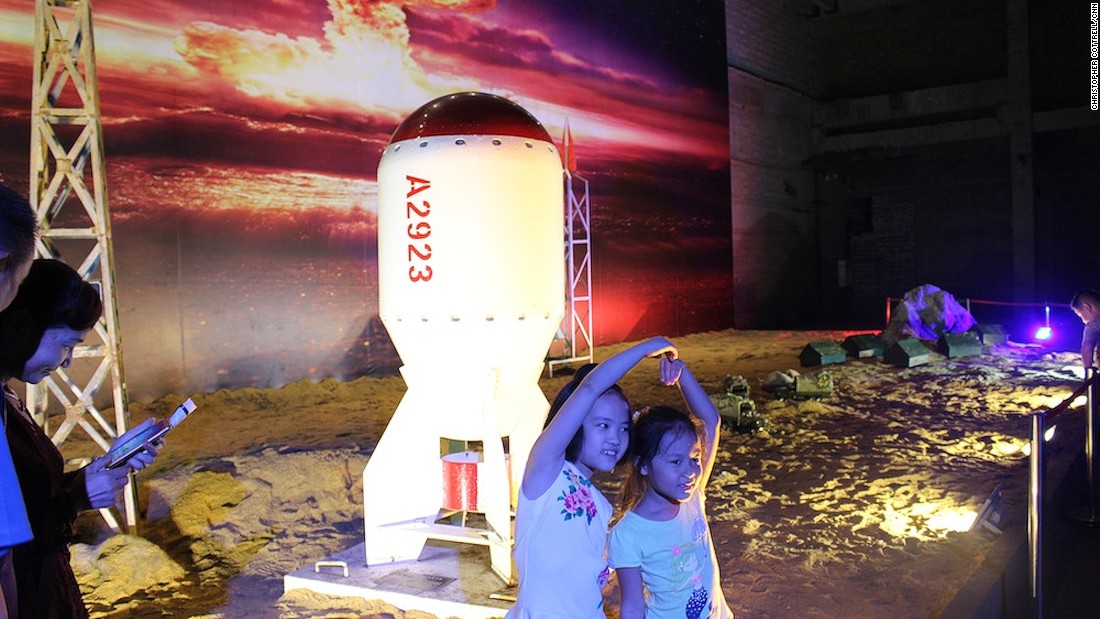 Children pose in front of a life-size replica of China&#39;s first atomic bomb, which was detonated during a nuclear test in 1964.
