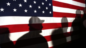 MYRTLE BEACH, SC - FEBRUARY 11:  Shadows are reflected on an American Flag as people line up to speak with Ohio Governor and Republican presidential candidate John Kasich at a restaurant in South Carolina following his second place showing in the New Hampshire primary on February 11, 2016 in Myrtle Beach South Carolina.  Kasich, who is running as a moderate, is expected to face a difficult environment in South Carolina where conservative voters traditionally outnumber moderates.  (Photo by Spencer Platt/Getty Images)