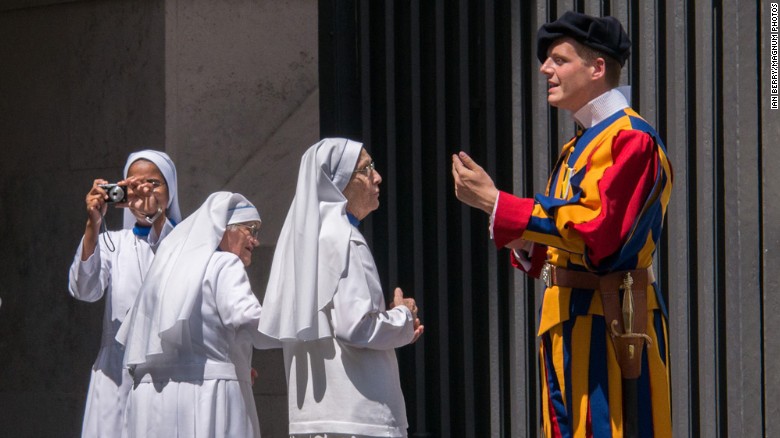 Italy.  Rome.  A group of nuns at the entrance to the Vatican take pictures and ask questions of the Swiss Guard on duty there.  2013