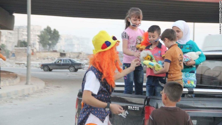 Anas al-Basha, dressed in his clown costume, plays with children on a roadside in Aleppo. 