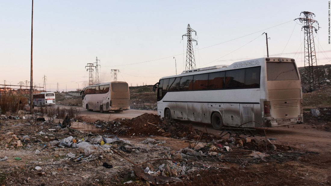 Buses drive through the Syrian government-controlled crossing of Ramoussa, on the southern outskirts of Aleppo, on December 18, 2016, during an evacuation operation of rebel fighters and civilians from rebel-held areas. / AFP / George OURFALIAN        (Photo credit should read GEORGE OURFALIAN/AFP/Getty Images)