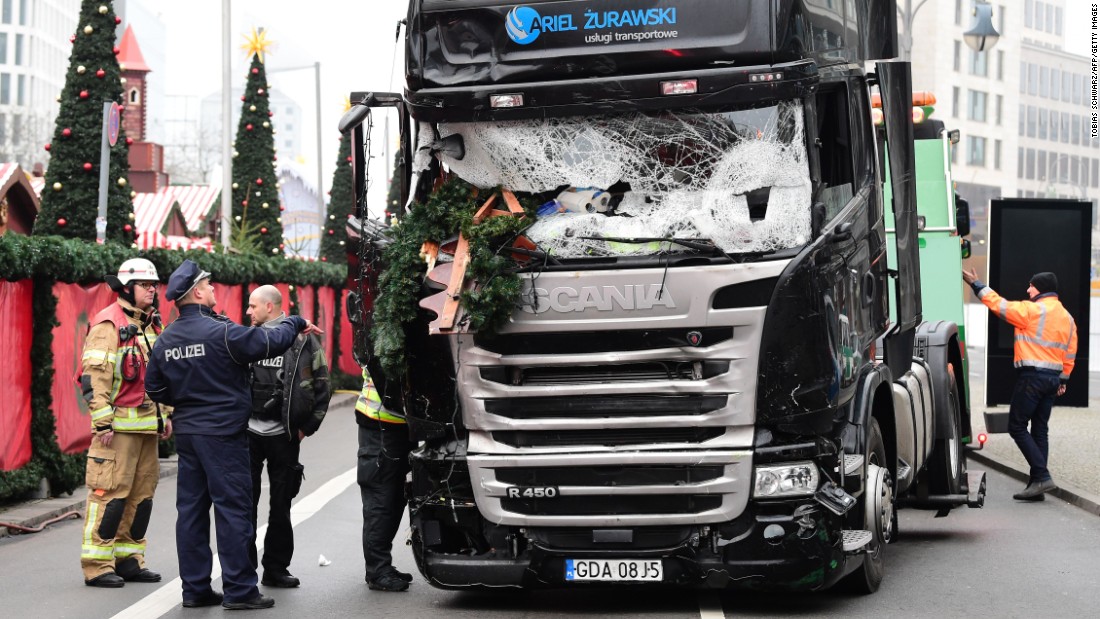 A policeman and firemen stand next to a truck on December 20, 2016 at the scene where it crashed into a Christmas market near the Kaiser-Wilhelm-Gedaechtniskirche (Kaiser Wilhelm Memorial Church) in Berlin.
German police said they were treating as &quot;a probable terrorist attack&quot; the killing of 12 people when the speeding lorry cut a bloody swath through the packed Berlin Christmas market.