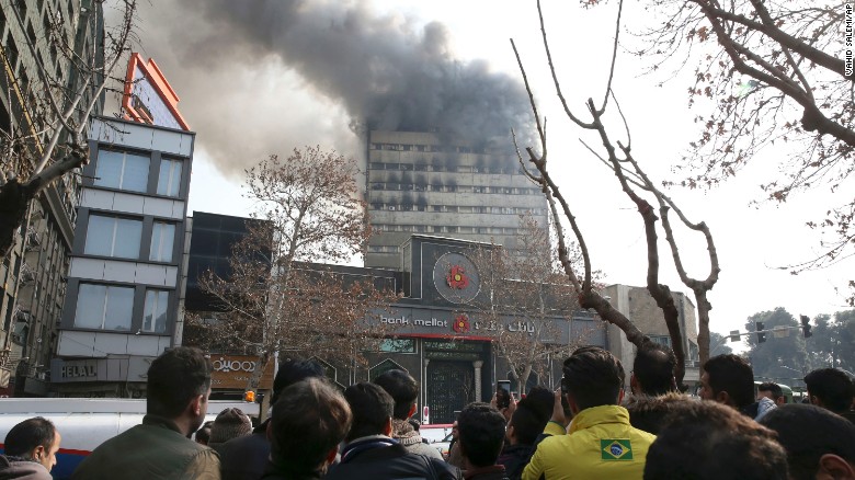 People watch as smoke rises from the windows of the Plasco building.