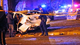 Police officers chat with a man in a car that was struck by a pickup.