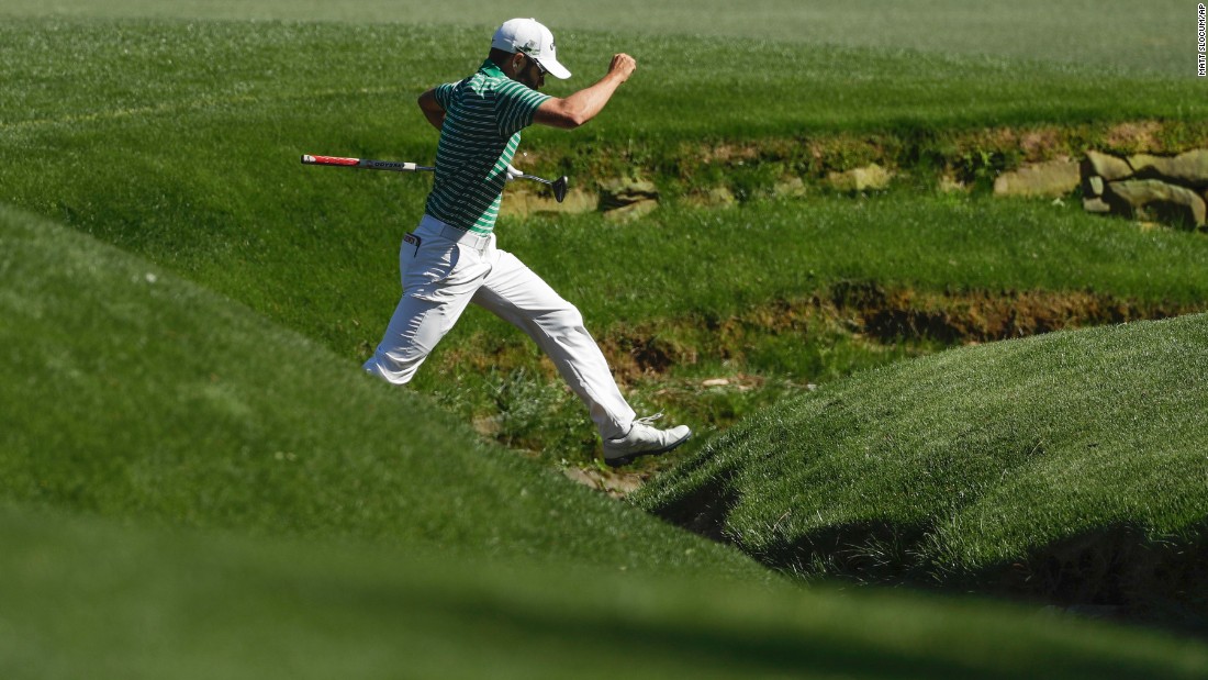 Adam Hadwin jumps across Rae&#39;s Creek while playing the 13th hole.