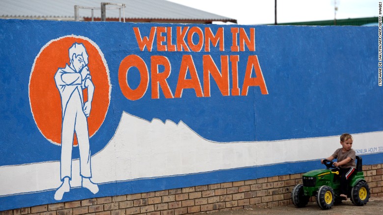A young South African Afrikaner boy plays by a painted wall reading &quot;Welcome in Orania&quot; in Afrikaans.