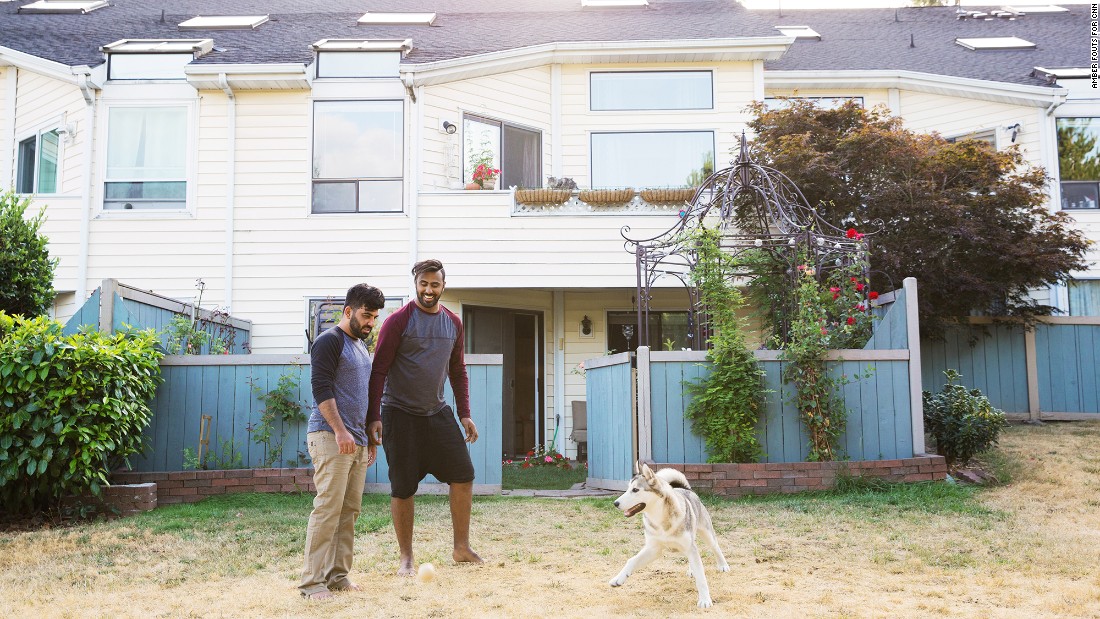 Hrebid and Allami play with their dog, Cesar, outside their home.
