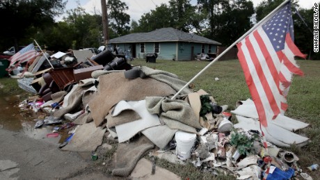 Tattered flags fly over a pile of water-soaked items as people clean up in a flood ravaged neighborhood Thursday, Aug. 31, 2017, in Houston. The city continues to recover from record flooding caused by Harvey. (AP Photo/Charlie Riedel)