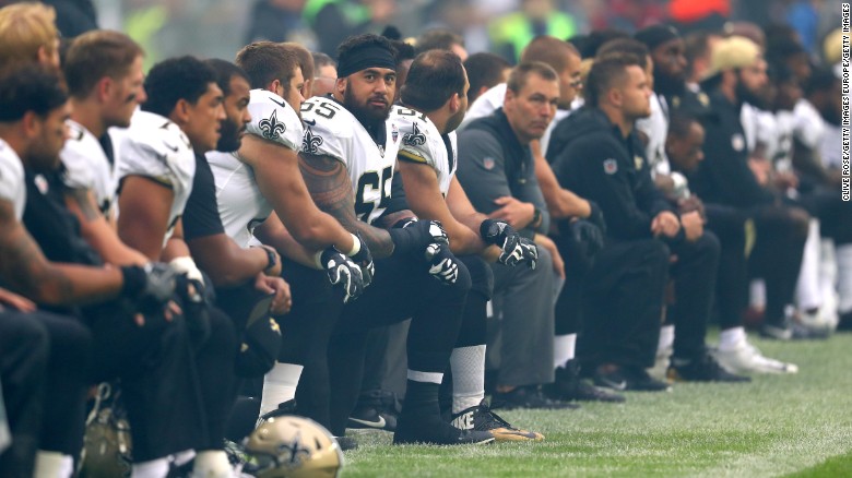 The New Orleans Saints team kneels before standing for the National Anthem in a game against the Miami Dolphins in London&#39;s Wembley Stadium. 